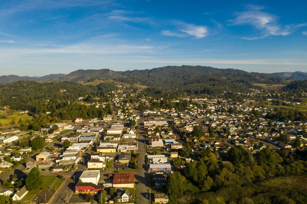 Aerial view of a small rural Oregon town surrounded by forested hills